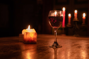 A glass of wine is on a table with candles Romantic Valentine's Day evening. Defocused Lights Background