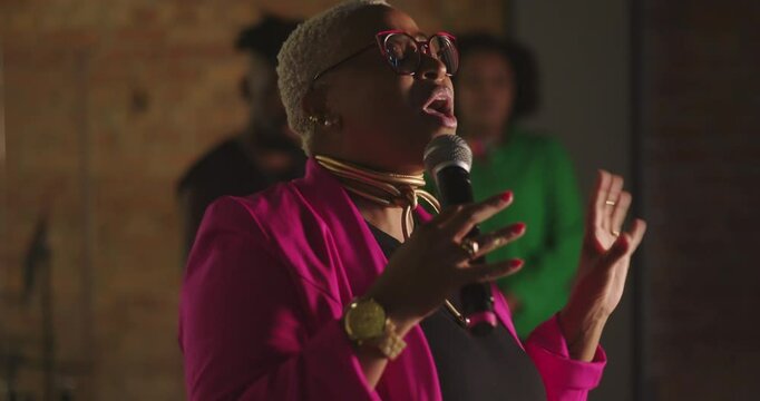 African descent woman preaching passionately during evangelical church service, holding microphone, joyful expression, spiritual leadership, engaging congregation with faith and energy