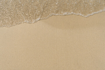 Summer waves crash on the sandy beach