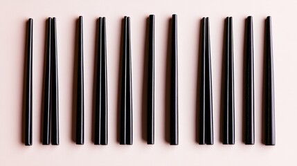 Black chopsticks arranged on a pastel pink background