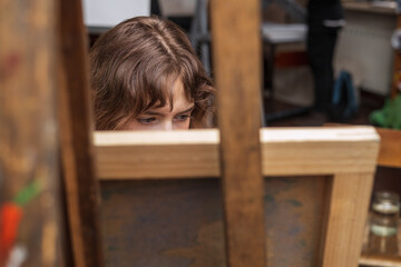 Girl artist in art studio painting on easel. 