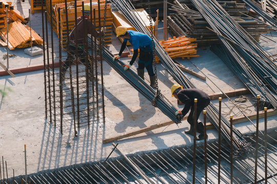 Construction Crew at Work, Dedicated workers skillfully handle steel rods and materials on bustling construction site, teamwork and essence of structural development
