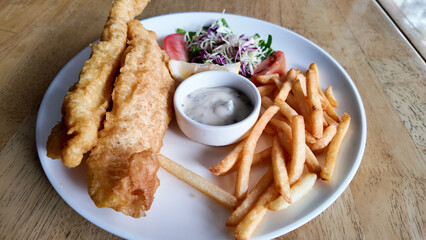 Crispy fish and chips served with tartar sauce and fresh salad