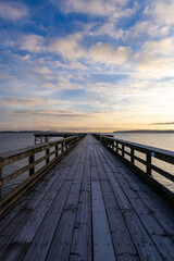 Obraz premium Wooden Pier Overlooking Calm Waters at Sunset with a Cloudy Sky