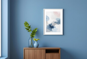 A photo frame featuring an abstract painting on a minimalist blue-colored wall with a vase and soft lighting