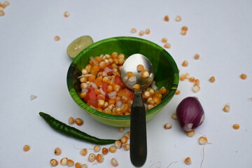 Boiled corn Chaat. Indian style corn salad that's sweet, spicy and tangy. It is mixed with chaat masala, roasted cumin powder, red chili powder, coriander leaves, onion and tomatoes. Indian snacks.