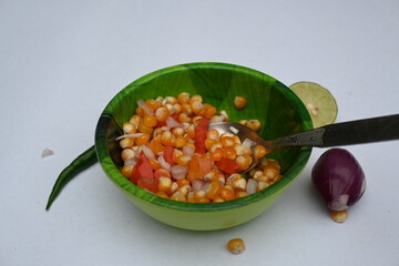 Boiled corn Chaat. Indian style corn salad that's sweet, spicy and tangy. It is mixed with chaat masala, roasted cumin powder, red chili powder, coriander leaves, onion and tomatoes. Indian snacks.