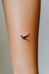 Obraz premium Arm tattoo with a black silhouette bird flying, on clean skin for body art