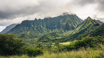 Fototapeta premium Lush green mountain range under a cloudy sky in a tropical paradise