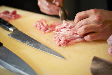 Hands cutting tuna with a knife