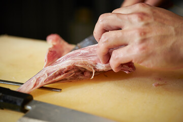 Hands cutting tuna with a knife