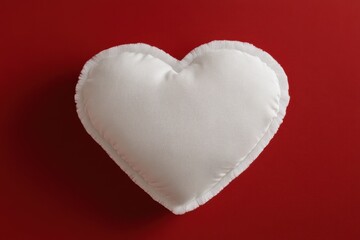 White heart shaped pillow with fringe on a red background