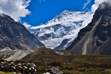 Majestic view of snow-covered Kanchenjunga peak under a clear blue sky, captured from the scenic Kanchenjunga Base Camp trek in the remote Nepalese Himalayas.