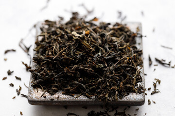 Fototapeta premium Japanese or Chinese jasmine tea leaf on black ceramic plate on white background.