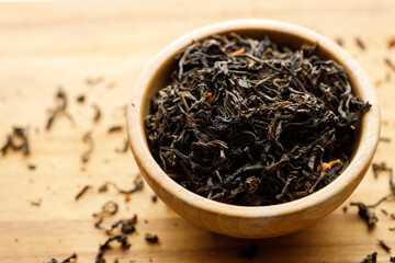 Japanese or Chinese jasmine tea leaf in wooden bowl on wooden background.