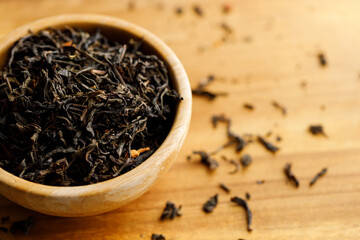 Japanese or Chinese jasmine tea leaf in wooden bowl on wooden background.
