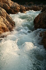 River flows among rocks; stream rushes during sunny day, nature scene, travel image