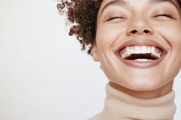 close-up of joyful androgynous individual laughing naturally wearing minimal makeup and simple turtleneck