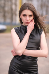 Portrait of a young beautiful brown-eyed long-haired girl in a black dress in nature.