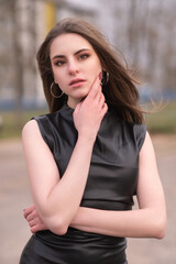 Portrait of a young beautiful brown-eyed long-haired girl in a black dress in nature.