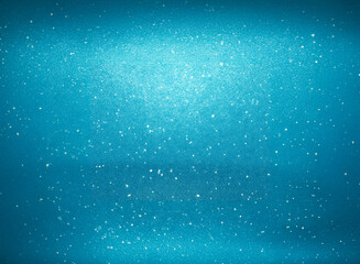 A textured teal backdrop with a subtle gradient from light to dark. Tiny white specks are scattered across the surface, resembling stardust or glitter.