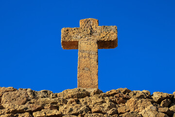 old stone cross against the background of the blue sky - Barcelona