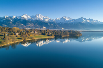 Obraz premium Peaceful lake surrounded by snow-capped mountains, offering a serene and picturesque winter landscape.