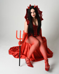 portrait of beautiful dark haired  pin-up model wearing elegant red dress with gothic fantasy...
