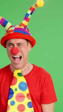 Clown pointing aside on green screen background