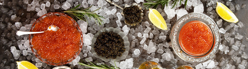 Natural black and red caviar on table. Natural omega. Caviar in transparent dish lies on ice. Lemon...