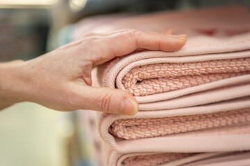 Woman hand takes towel from stack on shelf in supermarket close-up.