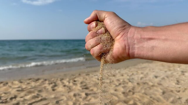 Grains of sand falling from a hand in slow motion