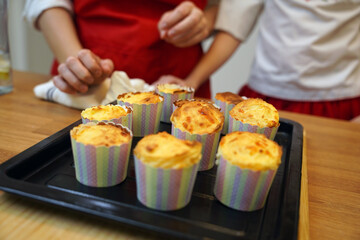 Mother and daughter in the kitchen in traditional Ukrainian costumes making cupcakes for Easter