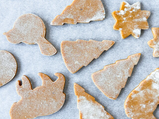 Assorted raw gingerbread cookie shapes on parchment paper
