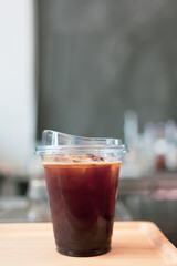 Iced black coffee americanoa in take away plastic cup on wooden table