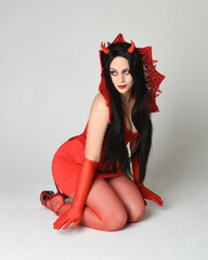 portrait of beautiful dark haired  pin-up model wearing elegant red dress with gothic fantasy...