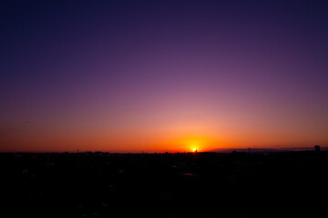 幻想的なグラデーションが広がる夕焼け空と都市のシルエット