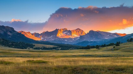 Obraz premium A majestic mountain range at sunrise with golden light hitting the peaks.