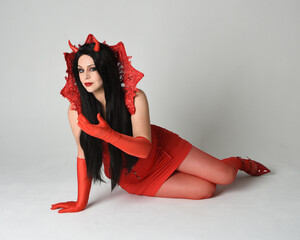 portrait of beautiful  female pin-up model wearing red dress with gothic fantasy burlesque...