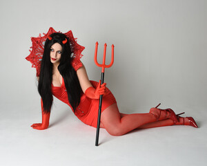 portrait of beautiful  female pin-up model wearing red dress with gothic fantasy burlesque...