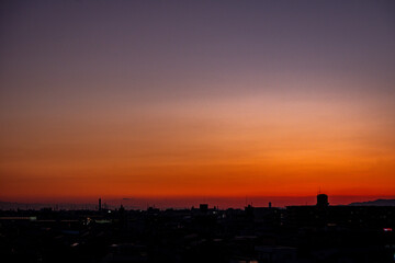 Naklejka premium 夕焼け空に染まる都市のシルエットとグラデーションの美しい空