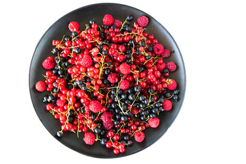 Red and black currant and loganberries on the black plate and white background.