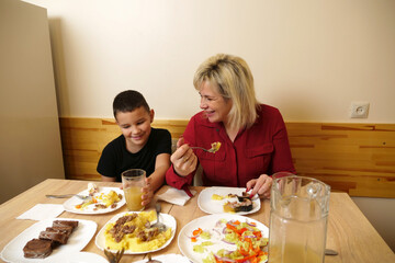 At the festive table, mother and son are treated to food and drinks.