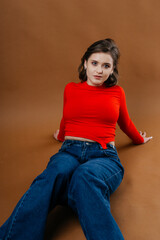 A fashionable young woman in a bold red top and wide-leg denim jeans strikes a dynamic and artistic...