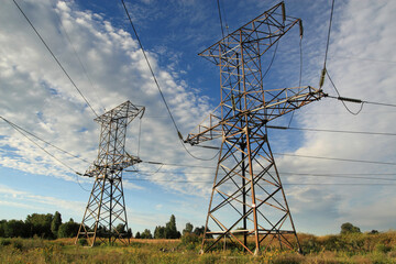 field, high-voltage power transmission line poles in the sun, against the blue sky © Марина Музыка