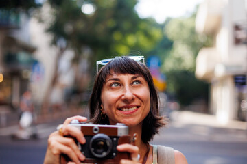 Girl walking around the city and taking pictures with a camera. young girl with a film camera in...