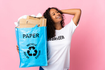Teenager cuban girl holding a recycling bag full of paper to recycle isolated on pink background...