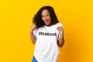 Teenager cuban volunteer girl isolated on yellow background celebrating a victory in winner position