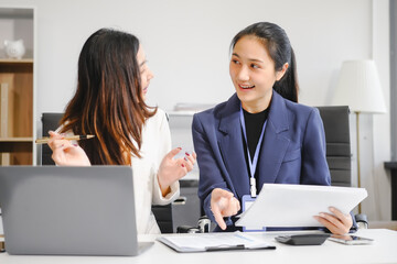 Two Asian female business woman sit desk,discussing business investments.They analyze financial data, explore market opportunities, and strategic growth to maximize returns ensure business success