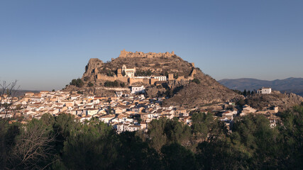 Fototapeta premium Old Spanish town with big fortified castle on hill top on sunny day, Moclin, Andalusia, Spain